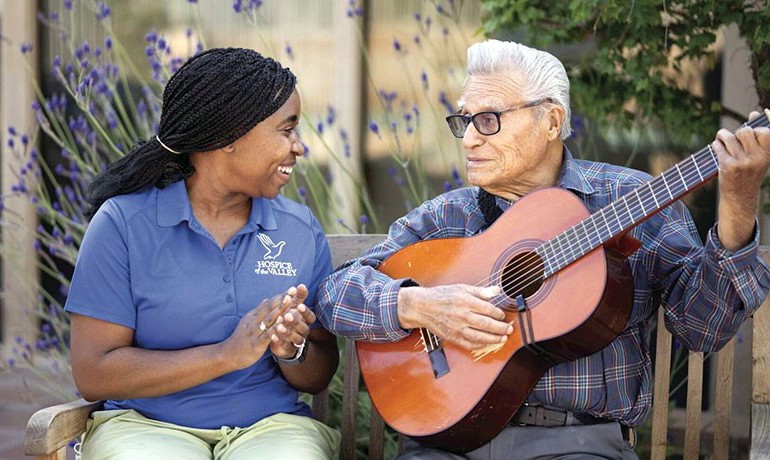 A man plays guitar for a smiling HOV employee