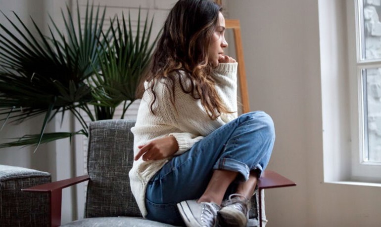 Young woman in chair looking pensive