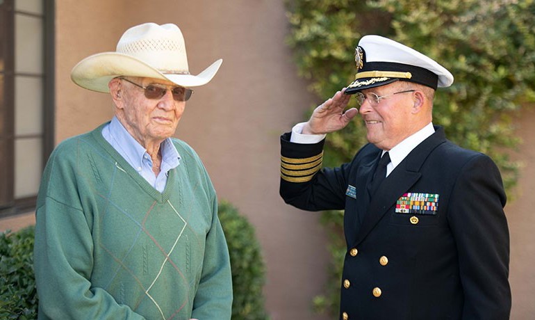 Man in dress uniform salutes older man