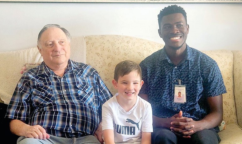 A HOV volunteer smiles with an HOV patient and the patient's grandson.