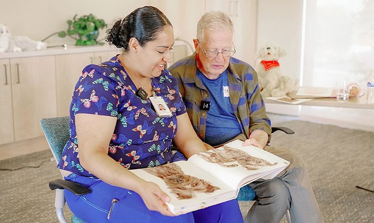 Caregiver Sonja Marti and Stephen Campbell page through a book of dog pictures together