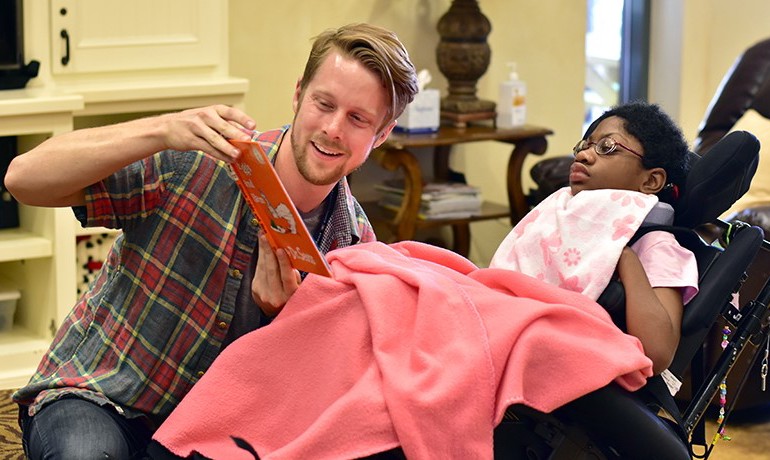 College student reading book to young patient