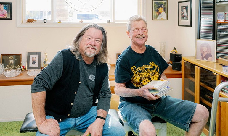 David Roberts smiling with his music collection and concert promoter Danny Zelisko