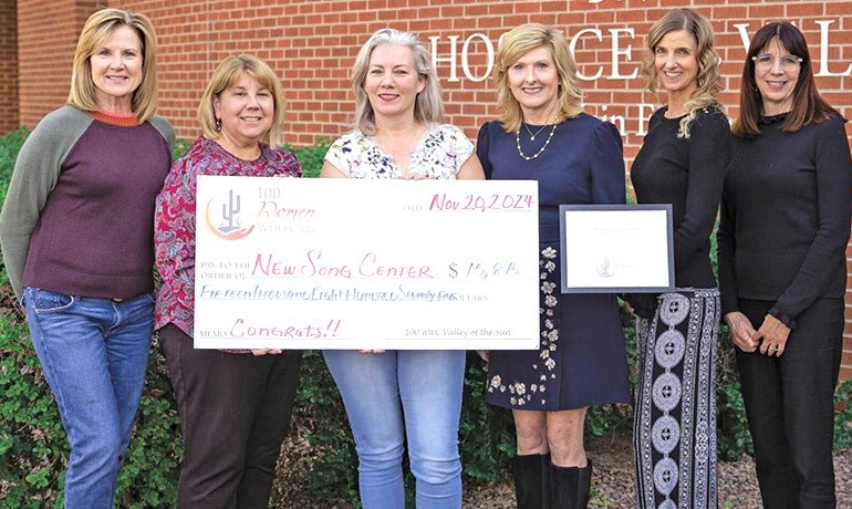 Six women from HOV and 100+ Women Who Care standing with a large donation check to the HOV New Song Center