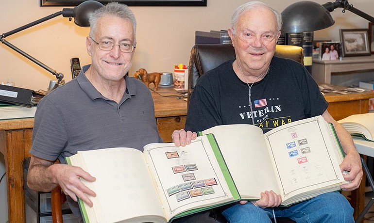 Kevin Lesk and Monroe Wingate holding stamp collection albums