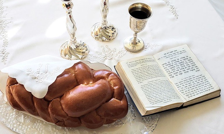 Challah, open book, and chalice on table