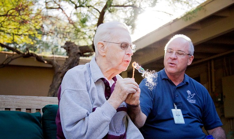 Patient blowing bubbles with caretaker